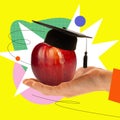 Human hand holding apple with graduation cap over abstract yellow background. Graduating university. Contemporary art Royalty Free Stock Photo