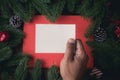 Human hand holding blank note paper on Christmas decorations background with pine leaf frame Royalty Free Stock Photo