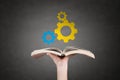 Human hand holding book with gears. Royalty Free Stock Photo