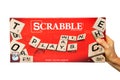 Human hand holding a box of Scrabble brand crossword leisure game