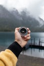 Human hand holding a compass and the lake surrounded with mountains in the background Royalty Free Stock Photo