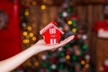 Human hand holding decorative red house against blurred background. Christmas and home comfort concept. Royalty Free Stock Photo