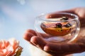 Human hand holding glass of herbal tea with dry rose buds Royalty Free Stock Photo