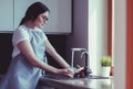 Human hand holding glass pouring fresh drink water at kitchen faucet Royalty Free Stock Photo