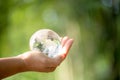 Human hand holding globe planet glass In green forest with bokeh nature lights. world environment day. concept for environment Royalty Free Stock Photo