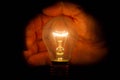 Human hand holding a light bulb to conserve energy darkness Royalty Free Stock Photo