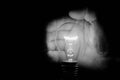 Human hand holding a light bulb to conserve energy darkness artistic conversion Royalty Free Stock Photo