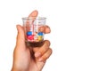 A human hand holding many colorful pills in a measuring cup of glass. Royalty Free Stock Photo