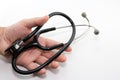 A human hand holding a medical doctor`s stethoscope which features a white background. Royalty Free Stock Photo