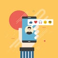 Human hand holding mobile phone with social network feedback emoticons.