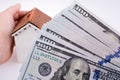 Human hand holding a model house by the side of aAmerican dolla Royalty Free Stock Photo