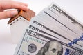 Human hand holding a model house by the side of aAmerican dolla Royalty Free Stock Photo