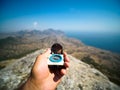 Human hand holding old compass in sunny day on blurred mountains and sea. Royalty Free Stock Photo