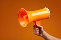 Human hand holding orange megaphone