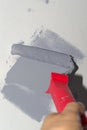 Human hand holding paint roller and gray stroke on white wall Royalty Free Stock Photo