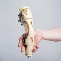 Human hand holding part of robotic mechanical bone prosthesis prototype. Bionic technology, beige human arm, engineering Royalty Free Stock Photo