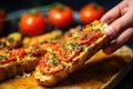 human hand holding a piece of grilled garlic bread topped with tomato slices