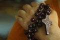 Human hand holding a rosary on the shoulder closeup. Junior young man hands praying holding a rosary with Jesus Christ Cross or Royalty Free Stock Photo