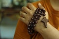 Human hand holding a rosary on the shoulder. Junior young man hands praying holding a rosary with Jesus Christ Cross or Crucifix. Royalty Free Stock Photo