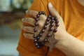 Human hand holding a rosary on the shoulder. Junior young man hands praying holding a rosary with Jesus Christ Cross or Crucifix. Royalty Free Stock Photo