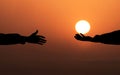 Human hand holding the Sun and giving it To another person. Helping hand Concept. Sunset Sun background. God`s salvation Royalty Free Stock Photo