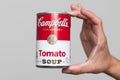 Human hand holding a tin can of Campbell`s Soup tomato soup