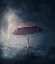 Human hand holding an umbrella sinking in the ocean. Surreal and dramatic scene of person drowning in the sea waters under the