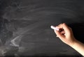 Human Hand holding white chalk on blackboard chalkboard black board background texture.