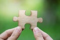 Human hand holding a wooden jigsaw puzzle with green background. Royalty Free Stock Photo