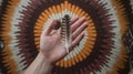 Person Holding Feather Against Colorful Decorative Wall Hanging Royalty Free Stock Photo