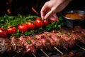 human hand layering marinated beef in turkish shish kebab skewers