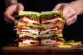 human hand layering sliced chicken on a club sandwich