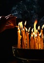 Human hand lights a candle in the church