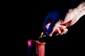 Human hand with a match lights a red candle Royalty Free Stock Photo