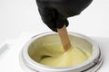 Human hand mixing wax with wooden sticks in wax melter