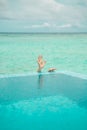 Human hand over water shot behind the edge of swimmig pool on background of Indian coean