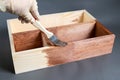 Human hand is painting brown a wooden crate