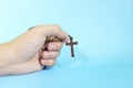 Human hand praying and holding a scapular rosary in blue background. Christianity and Catholicism concept. Royalty Free Stock Photo