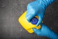 Human hand in protective glove opening a yellow bleach bottle Royalty Free Stock Photo
