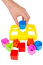 Human hand puts wrong shape into shape sorter toy isolated