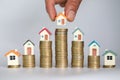 Human hand putting house model on coins stack. Concept for property ladder, mortgage and real estate investment Royalty Free Stock Photo