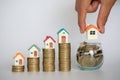 Human hand putting house model on coins stack. Concept for property ladder, mortgage and real estate investment Royalty Free Stock Photo