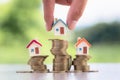 Human hand putting house model on coins stack, planning savings money of coins to buy a home concept, mortgage and real estate