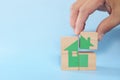 Human hand putting together house icon puzzle made of wooden blocks. Property real estate investment, security and home ownership Royalty Free Stock Photo