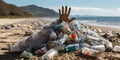 A human hand reaches out from under a mountain of household plastic waste on the ocean shore Royalty Free Stock Photo