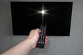 Human hand with a remote control in front of a black tv ice Royalty Free Stock Photo