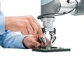 Human hand and robotic gripper working on circuit board Royalty Free Stock Photo