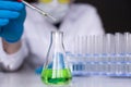 Human hand in rubber glove dripping a green reagent from the pipette into a flask as a process, close up, selective Royalty Free Stock Photo