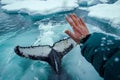 A human hand touching the icy water, with a massive whale waving its tail Royalty Free Stock Photo