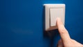 Human hand turn off a power button on a blue wall - side view Royalty Free Stock Photo